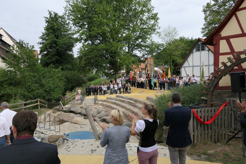 Der Wasserspielplatz ist er�ffnet - im Hintergrund die Fahnenabordnungen der M�mbriser Vereine